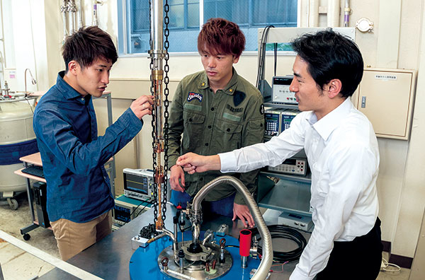 Tetsuo Kodera, Masahiro Tadokoro, and Seiya Mizoguchi prepare for an experiment to evaluate a quantum bit at ultra-low temperature. This large refrigerator (2 meters underground) is used for experiments requiring a large magnetic field.